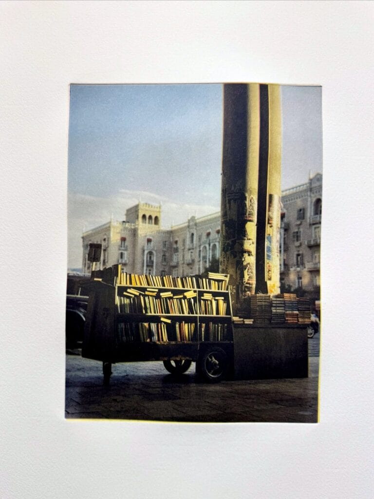 Color photogravure of a bookseller’s cart beside tall columns, printed at a Prints on Paper Studio workshop
